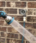 Outdoor Faucet Handle Replacement Round Wheel Spigot For Hose Bibb Leaky Outdoor Faucets Includes Screws Metal Silver Pewter 1.25 Inch Long 3.75 Inch Wide, attached to a brick wall with a hose in use