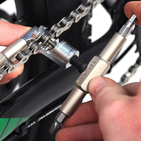 Mountain Bike Tool Kit With Replaceable Sticks And Bracket Two Tire Levers Eight Bits Chain Breaker in use on bike chain