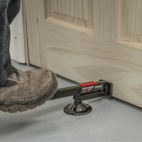 Swivel Type Door And Board Lifter With Hands Free Foot Operated Lift lifting a wooden door, showing black construction tool.