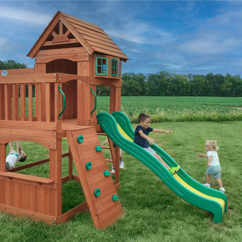 Children playing on Atlantis Cedar Wood Swing Set With Wave Slide And Raised Clubhouse Featuring Rock Wall in backyard