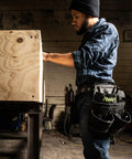 Person wearing Durable Premium Pro Grade Tool Belt Rig With 18 Pockets And Quick Access Tool Loops in workshop setting.