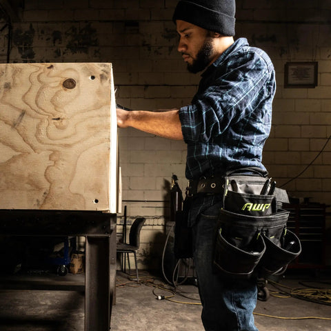 Person wearing Durable Premium Pro Grade Tool Belt Rig With 18 Pockets And Quick Access Tool Loops in workshop setting.