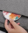 Watercolor Flowers Wireless Charger 10W Fast Charge Pad being placed into a grey bag compartment, showcasing portability.