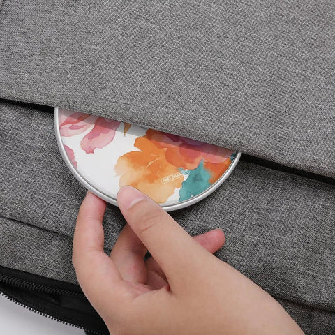 Watercolor Flowers Wireless Charger 10W Fast Charge Pad being placed into a grey bag compartment, showcasing portability.