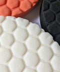 Badass 6-Inch Foam Buffing Pads for Cars in white, orange, and black, showcasing hexagonal texture for effective polishing.