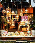 Storefront window with "We're Open" sign and decorative birdcages inside, showcasing Open And Closed Sign 12x16 Inch Double Sided Vinyl Sign.