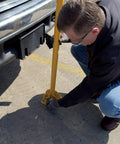 Person installing Tough As Nails Ground Mount Heavy Duty Steel Fold Down Bollard Padlock Secured Parking Lot Barrier.