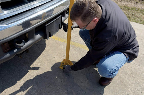 Person installing Tough As Nails Ground Mount Heavy Duty Steel Fold Down Bollard Padlock Secured Parking Lot Barrier.