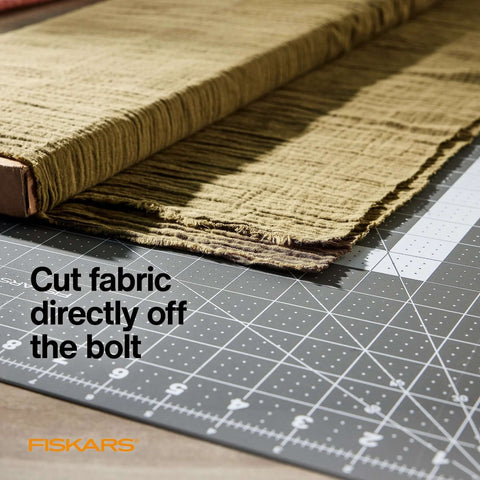 Fiskars self-healing cutting mat with folded fabric on top, gray grid surface, 24 x 36 inches