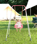 Child using 3-In-1 Toddler Swing Set With Metal Stand For Indoor Outdoor Use in backyard, pink baby seat, camping tents in background