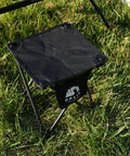 Two Pack Folding Camping Stool With Upgraded Latch Buckle on grass, black 600D Oxford cloth, steel frame shown
