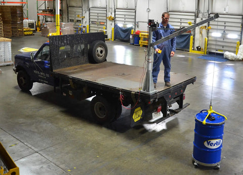 Smooth Operator DC Powered Jib Crane With Galvanized Build And Telescoping Boom Handles 1500 Pounds Easily For Real Workshops Using 360 Swivel Design, hoisting a barrel on a truck.