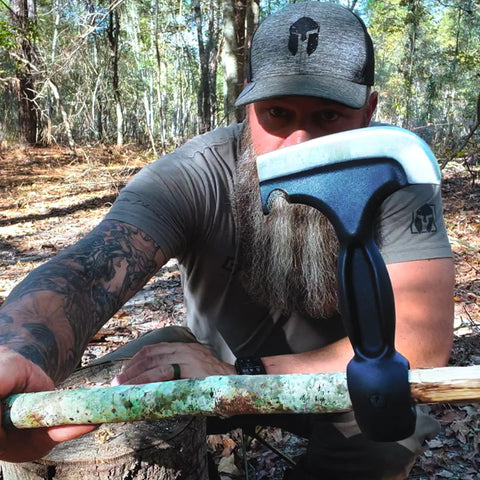 Man holding Five In One Survival Hatchet Head With Skinner Ulu Hammer Ripper And Gut Hook Leather Sheath in the woods.