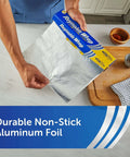 Person holding nonstick aluminum foil for easy cooking and mess free cleanup, perfect for casseroles and roasts, 130 sq ft, 12 inch wide.