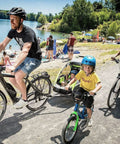 Family biking near lake with kids trailer using Bike Trailer Hitch Connector And Cycling Adapter For Kids Trailers Cargo And Pet Trailers