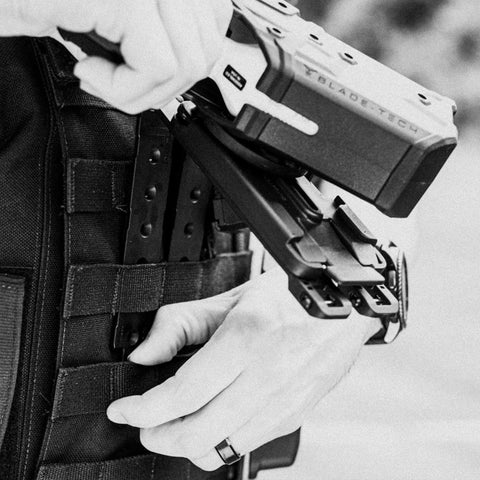 Person securing Rock Solid 3 Inch Molle Lok Clips onto tactical vest with nylon webbing, ideal for outdoor gear.
