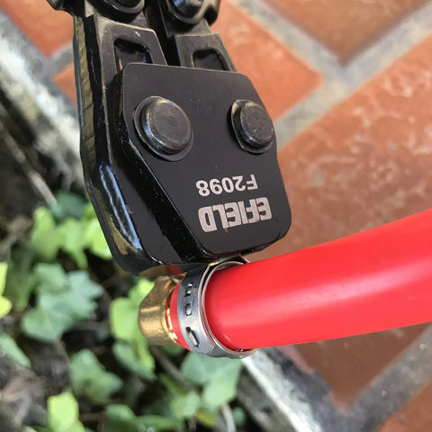 Pro Grade Pex Cinch Clamp Crimp Tool Kit With Stainless Steel Clamps on red pipe outdoors.