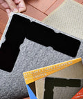 12 Pack Double Sided Rug Tape With Corner Grippers being applied to rug on hardwood floor with packaging box