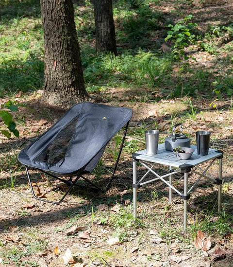 Ultralight Low Profile Camping Folding Chair With Side Pocket And Carry Bag 7.5 Inch Seat Height next to a foldable table outdoors.
