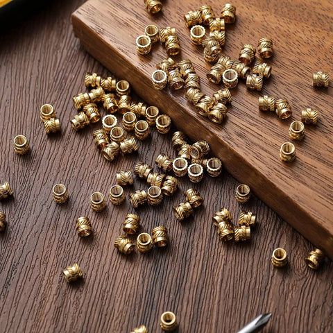 Bulk Pack of 300 Brass M4 Heat Set Threaded Inserts Knurled For Plastic on wooden surface