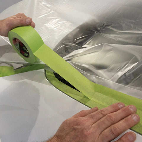 Applying High Performance Green Masking Tape 401 Plus For Clean Paint Lines on a car surface, showcasing superior adhesion.