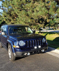 SUV with Two Pack 60W 4 Inch LED Work Light Bar Set With Flood And Spot Combo installed on front bumper, parked on road.