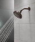 Five Setting Raincan Shower Head With H2Okinetic Spray In Venetian Bronze, Easy Clean Touch Nozzles on a tiled bathroom wall