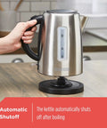 Person holding 1.7L Cordless Electric Kettle In Sleek Silver With Automatic Shutoff And Boil Dry Protection on kitchen counter.