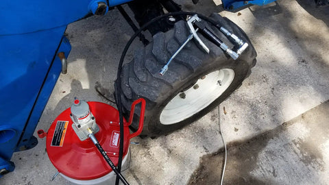 Pneumatic Grease Pump For 25-50Lb Pails, 40:1 Ratio Up To 4,000 PSI connected to tire for efficient lubrication.