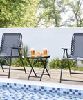 Outdoor Folding Round Patio End Table With Silk Tempered Glass Top And Lightweight Steel Frame set up by a poolside with two chairs