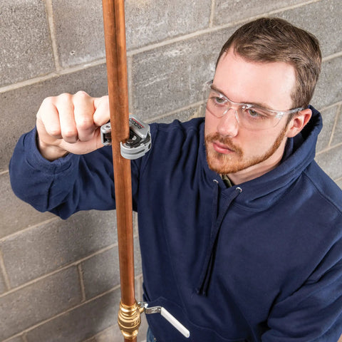 Person using Compact Auto Feed Tubing Cutter For Tight Spaces, 1/4 To 1-1/8 Inch on copper pipe in restricted area