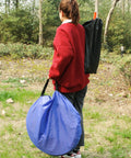 Person carrying blue bag for Dog Agility Training Starter Kit With Tunnel, 13 Weave Poles, Adjustable Hurdle, outdoors.