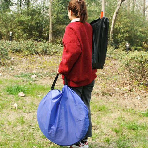 Person carrying blue bag for Dog Agility Training Starter Kit With Tunnel, 13 Weave Poles, Adjustable Hurdle, outdoors.
