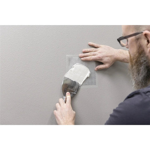 Person applying Drywall Patches Kit With Rustproof Aluminum Plate Self Adhering Mesh For Quick Wall Repairs No Pre Plaster Needed