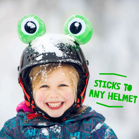 Child wearing Totally Fun Frog Helmet Accessory Set With Sticky Hook And Loop Fastener Adhesive Eyes And Ears Cover For Snowboarding Skiing Biking Cycling Skating For Kids And Adults Helmet Not Included, featuring plush frog eyes on helmet in snowy setting.