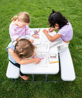 Three children coloring on a Compact Kids Picnic Table With Foldable Benches Under The Table And Built In Carry Handle For Easy Transport.