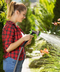Woman using Stainless Steel Garden Hose 25 Ft Heavy Duty Flexible Water Hose With 10 Function Spray Nozzle in garden.