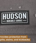 Close-up of Hudson Durable Goods logo on gray waxed canvas tool apron, showcasing spill-resistant material.