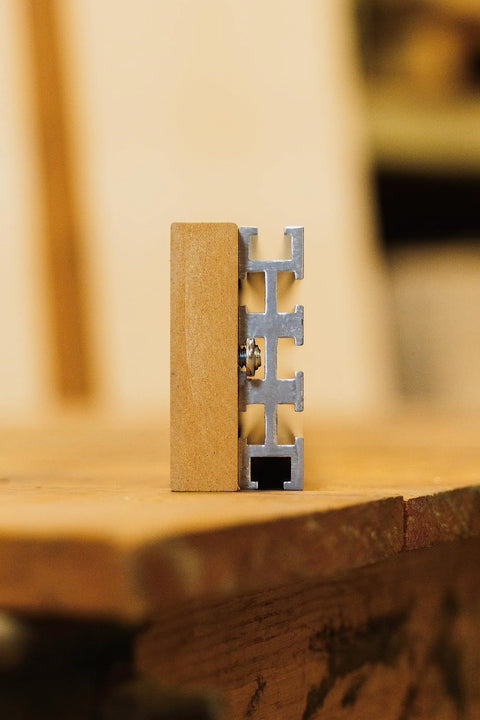 Heavy Duty 94 Inch Aluminum Multi T Track With Eight Precision Slots For Custom Jigs And Workbenches Plug And Play Build Premium 6061 T6 Anodized Made In USA showing close-up of aluminum track side view with wooden block.