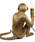 Dope Monkey Desk Lamp Modern Table Light with resin sitting monkey figurine holding a brass socket and twisted fabric cord