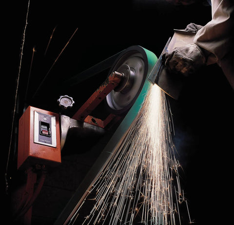 Cloth Grinding Belt 577F 3x132 In 80 YF-Weight, Alumina Zirconia Blend in use on metal, creating sparks during grinding.