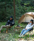 Two people sitting in Ultralight Camping Folding Beach Chair With Anti Sinking Large Feet And Back Support Webbing by a tent in the woods.