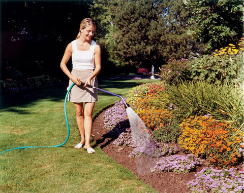 Person watering garden with ColorMark Soft Rain Watering Spray Wand 30 Inch Gold Lightweight Yet Durable With One Touch Lever Valve.