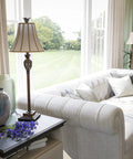 Tall Iron Lace Floor Lamp With Golden Ruby Finish, Classic Style And Ornate Scrollwork in a cozy living room setting near a window.