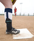 Close-up of Airsport Ankle Brace For Chronic Ankle Instability worn on left leg during baseball game on dirt field.