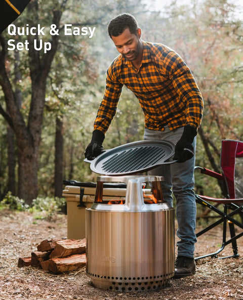 Man setting up Bonfire Cast Iron Grill Cooking Bundle 2.0 with Smokeless Fire Pit Stand in forest