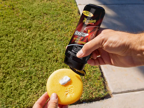Person applying Scratch-X Car Scratch Remover For Fine Scratches And Blemishes Quick Fix on a foam pad outdoors