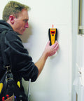 Slick All In One Stud Finder Pins Wood Metal And Live Ac Wires Fast With A Bright Lcd Screen and Pinpoint Focus being used on a wall.