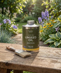 Natural Linseed Oil Wood Protector And Clear Varnish 500 Ml can with a paintbrush on wooden table in garden setting.