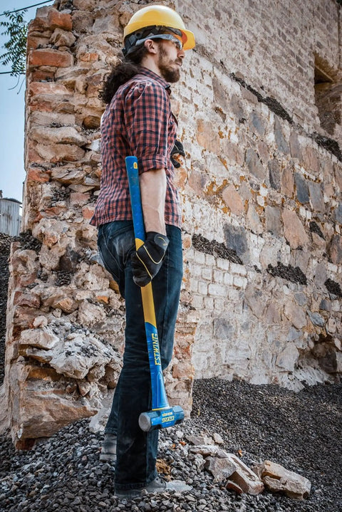 Worker holding 6 Pound Heavy Duty Hard Face Sledge Hammer Beast For Demolition And Stake Driving With 36 Inch Fiberglass Handle